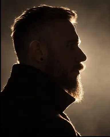 Profile of a bearded man in total shadow, a thin glowing rim tracing his forehead, nose, lips and beard