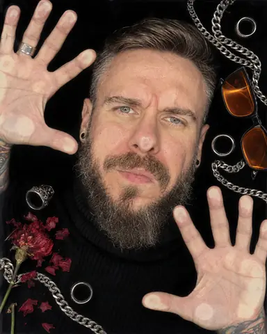A bearded man's face pressed flat against scanner glass, nose and cheek flattened, silver rings and chains around