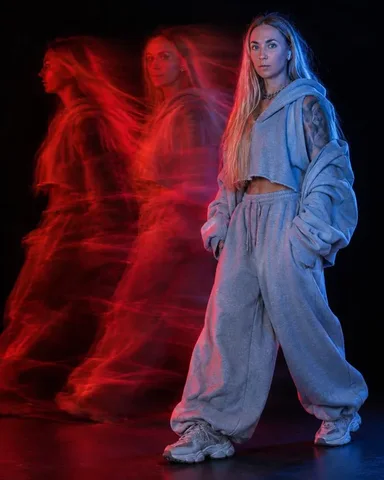 A bearded man in a frayed gray hoodie turns his head to the side, a red ghostly version of his face overlaps behind him.