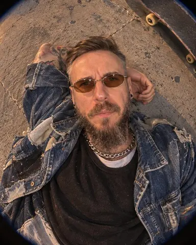 A bearded man lies on the ground looking up into the lens, the street curving around him in warm light