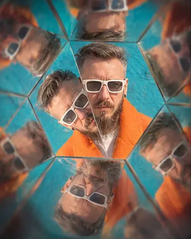 A bearded man's face in a central triangle, repeated six times into a hexagonal kaleidoscope pattern
