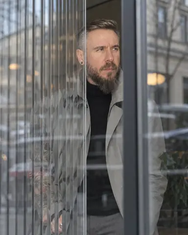 A bearded man seen through reeded glass, face clear in a smooth vertical strip, his body broken into thin slices