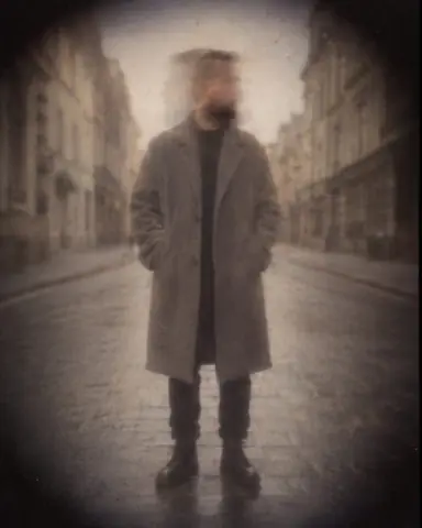 Soft pinhole view of a man in a gray coat on an empty street, his head doubled by a translucent ghost turn
