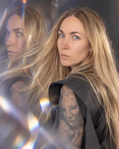 A woman with long blond hair turns her head, hair swinging, a translucent prism ghost of her face and hair beside her