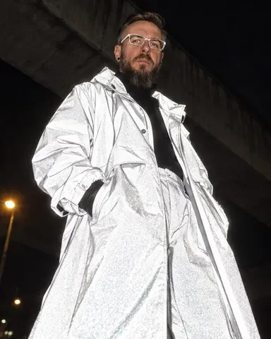 Waist-up shot of a man turning his head away, the hood edge and shoulders of his coat burning flash-white