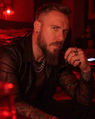 Close portrait of a bearded man in deep red side light, face three-quarters, eyes sharp, the background melting