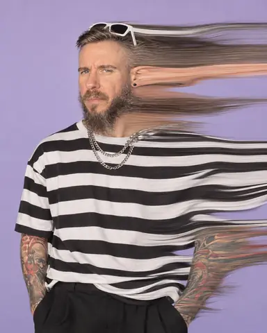 A bearded man turns his head during a slit scan, one side of his face stretched into a ribbon, both eyes sharp