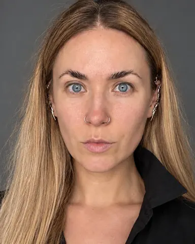 Frontal close-up of a woman with long blond hair, calm gaze, head slightly tilted, twin catchlights, silver ear-climbers