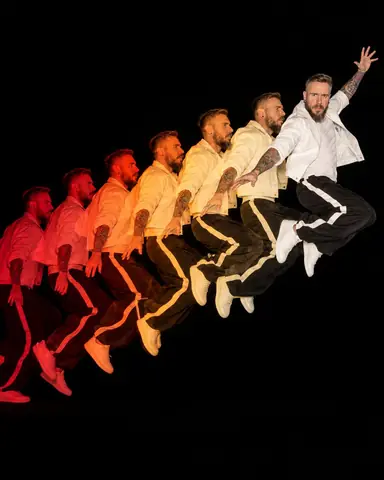 A bearded man jumps left to right in seven colored phases from red to white, the white peak phase facing the camera