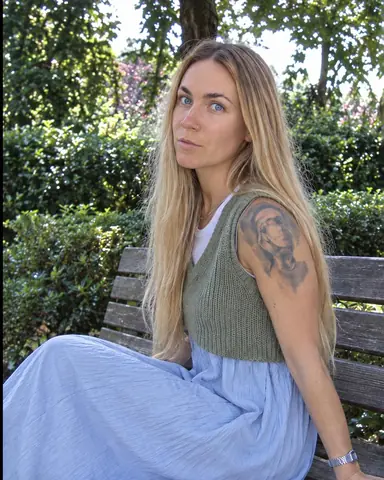 A woman with long blond hair sits sideways on a wooden bench, fingertips on the slats, sky gaps behind fringed purple