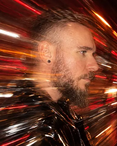 Profile of a bearded man streaked by a zoom burst, only his eye and beard frozen sharp by flash