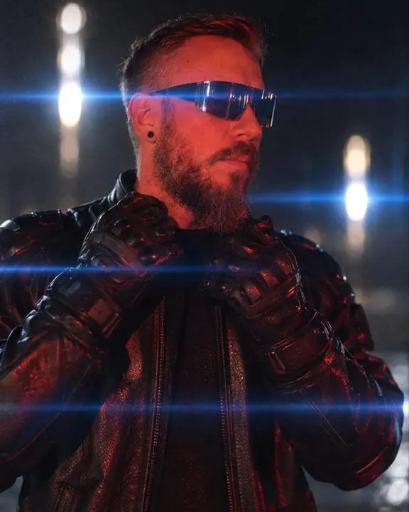 A man in black racing gloves adjusting his jacket collar, two parallel blue flare lines cutting the frame