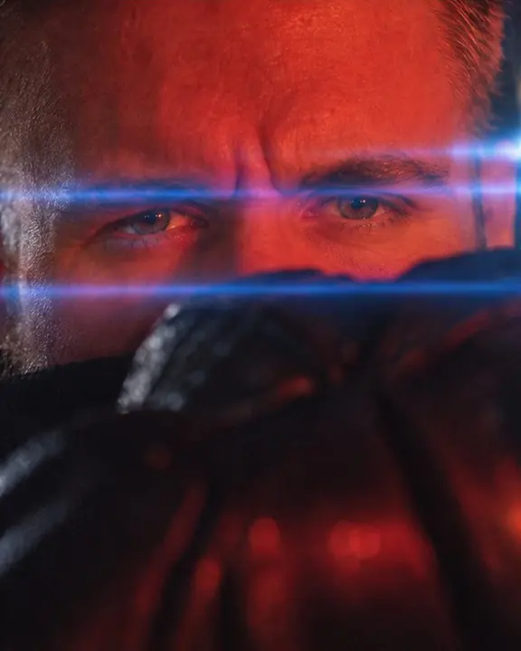Close-up of a bearded man's eyes in red light between two parallel blue horizontal flare lines
