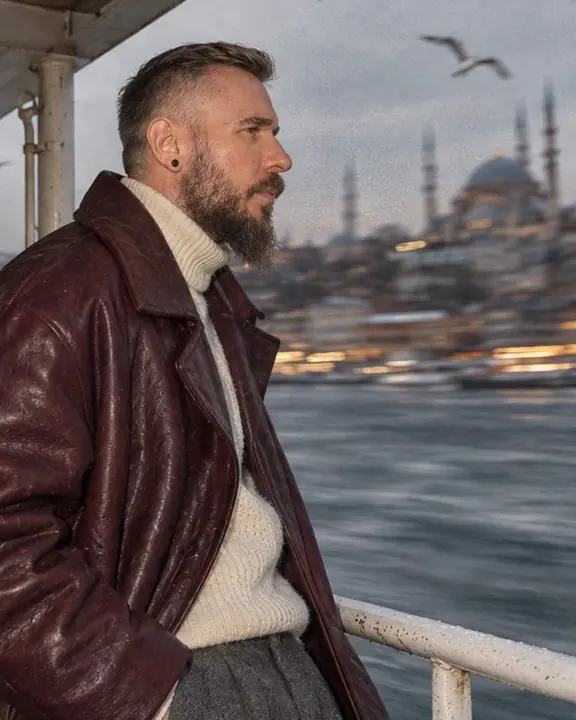 Profile of a bearded man on a ferry, mosque domes on the Bosphorus shore blurred behind him