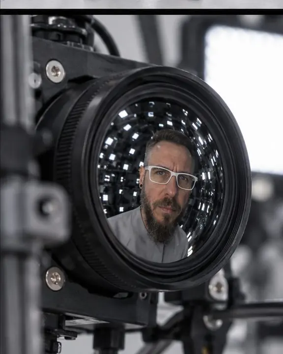 A single camera node and LED panel on the dome, a man's small reflection visible in the camera lens