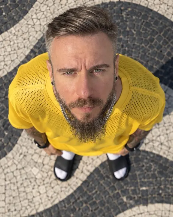 Close overhead shot of a bearded man's face looking up at the drone, black-and-white mosaic around his head