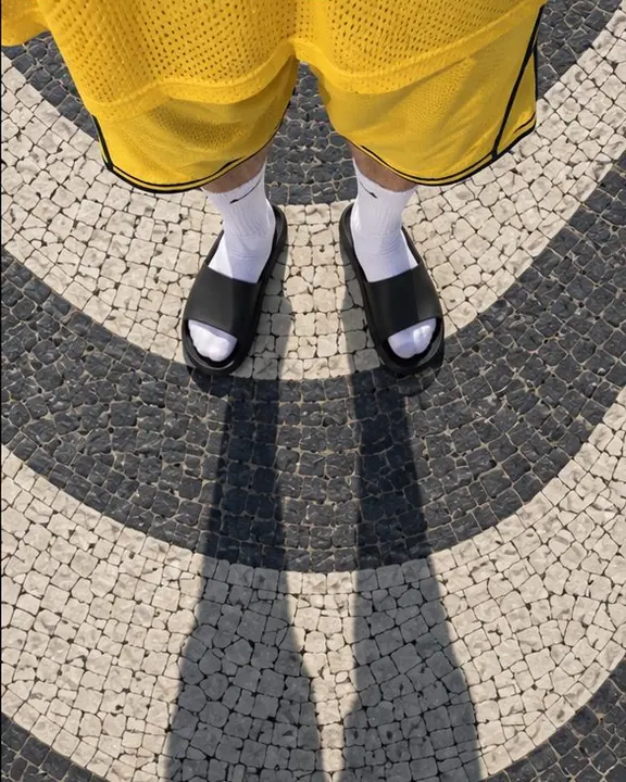 Black slides and white socks on Copacabana's black-and-white wave mosaic, seen from directly above