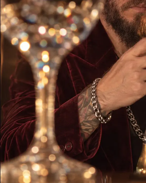 Caustic sparkles and a burgundy velvet sleeve seen through the stem of a crystal glass in warm light