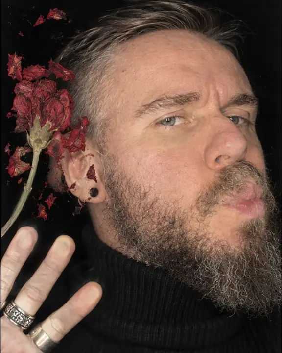 A man's face turned slightly with lips touching the scanner glass, a crushed red flower beside it on black