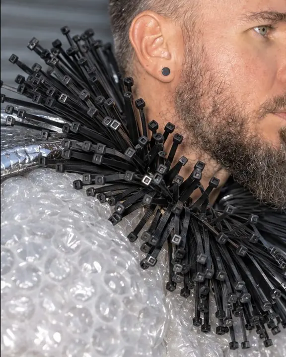Close-up of a black cable-tie ruff against a bubble-wrap shoulder, flash glinting on the plastic