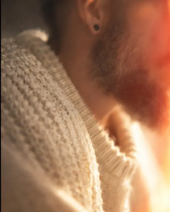 Cream knit texture sharp in a thin diagonal band, a red light leak glowing across the soft background