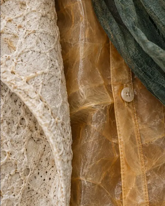 Macro close-up of irregular mycelium growth texture meeting the edge of a translucent amber cellulose shirt