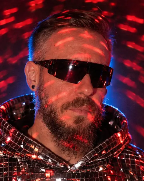 Head and shoulders of a bearded man, his features frozen sharp while curved red light streaks cross his face
