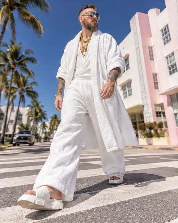A man in all white walks across a zebra crossing on Ocean Drive in hard noon flash light