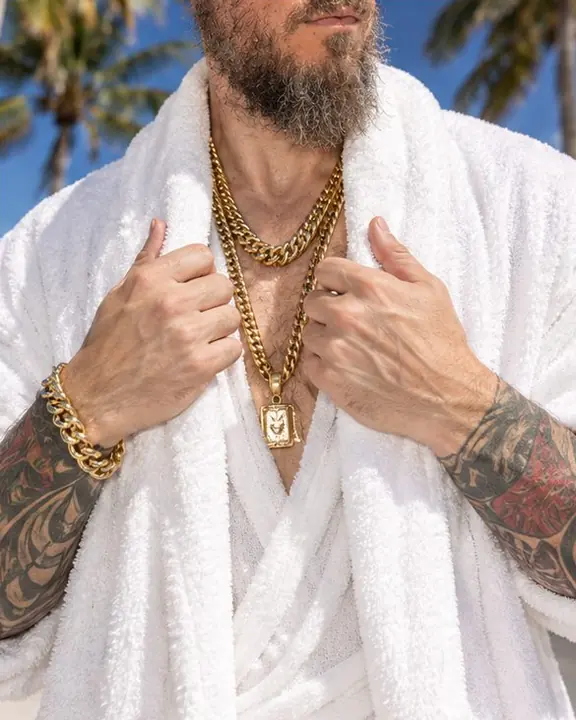 Layered gold chains on white terry cloth, lit by a hard direct flash in the noon sun