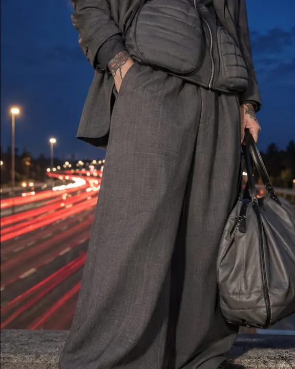 Detail of a padded gray blazer-track jacket hip, red traffic light streaks blurred in the background