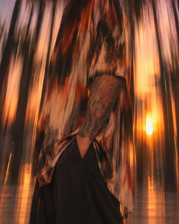 Detail of a rust-and-ink silk shirt print stretched into vertical streaks by camera movement