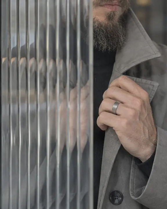 A hand and a turned-up funnel collar seen through reeded glass, sliced into repeated vertical strips
