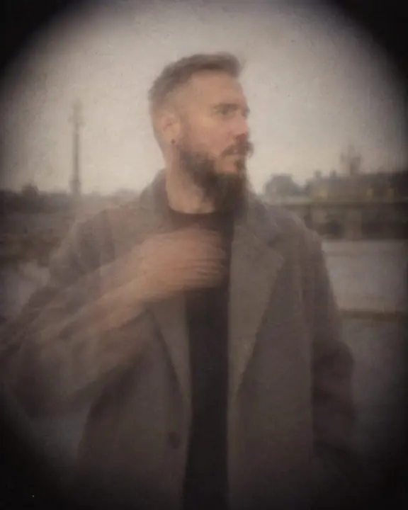 Half-length soft portrait of a man in a stone-gray coat, one arm leaving a translucent ghost as it moved
