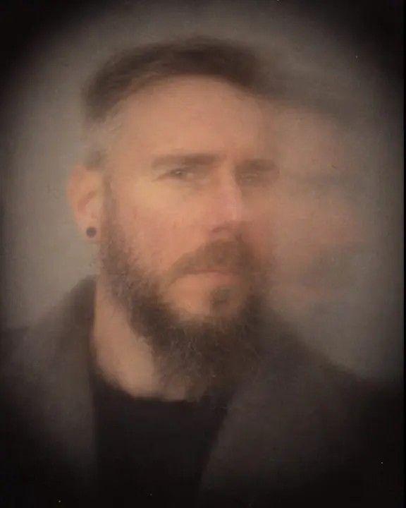 Close soft pinhole portrait of a bearded man, his face evenly soft with a slight ghost on one side