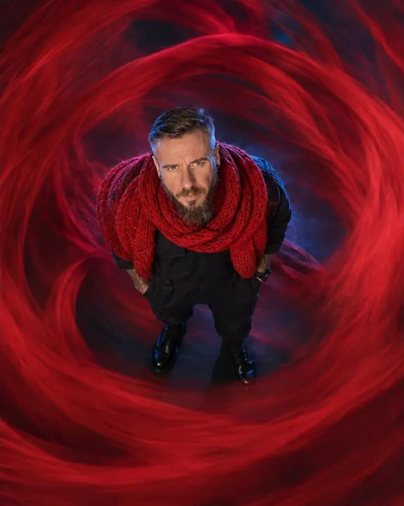 Overhead view of a red vortex of blurred knit fabric with a still man standing at its center