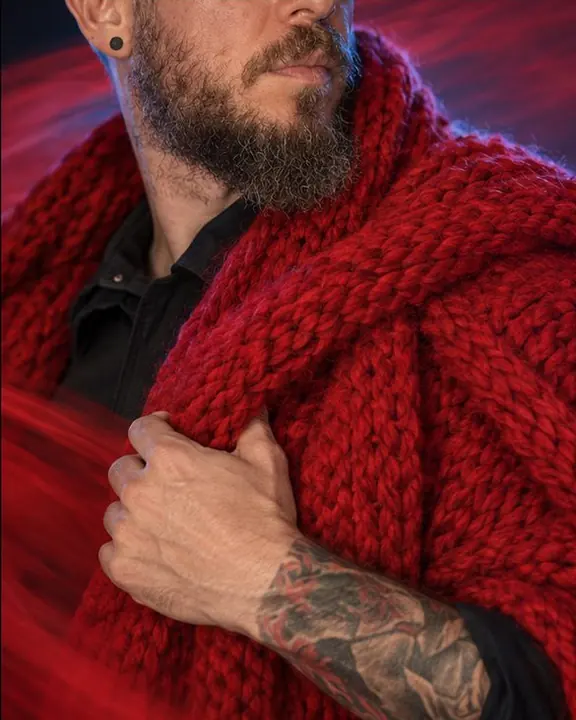 Detail of chunky red knit texture sharp where the scarf rests on a shoulder, the rest smeared into motion