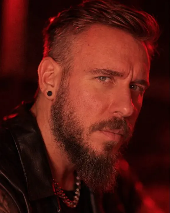 Close portrait of a bearded man in deep red side light, face three-quarters, eyes sharp, the background melting