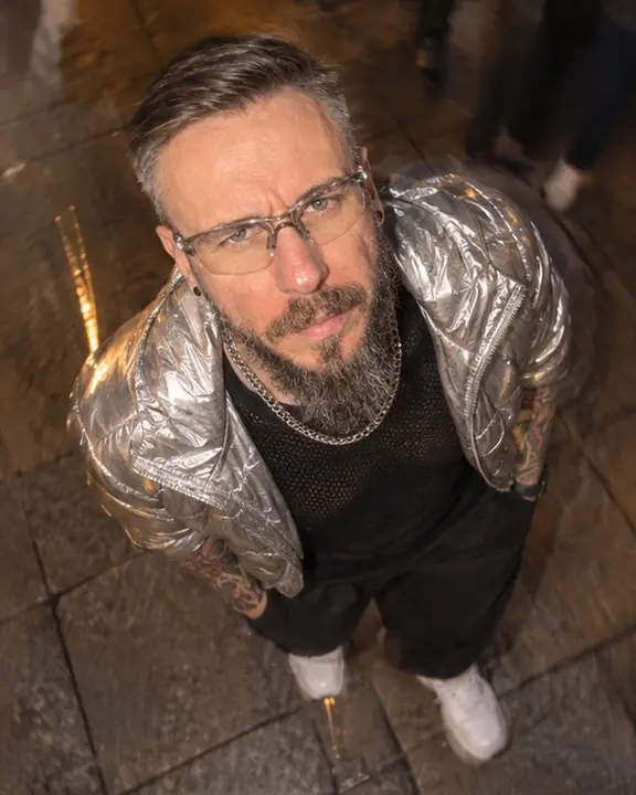 High-angle view of a bearded man looking up into the flash, sidewalk and light streaks swirling around him