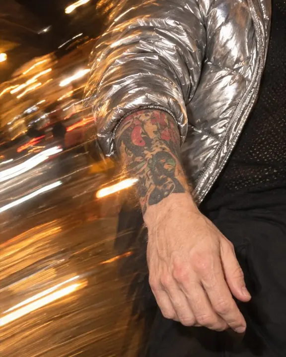 A silver puffer sleeve and hand frozen by flash, streaks of amber light passing through the frame