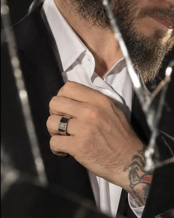 A mirror shard reflecting a white shirt collar and a silver ring, a sharp splinter of light across it