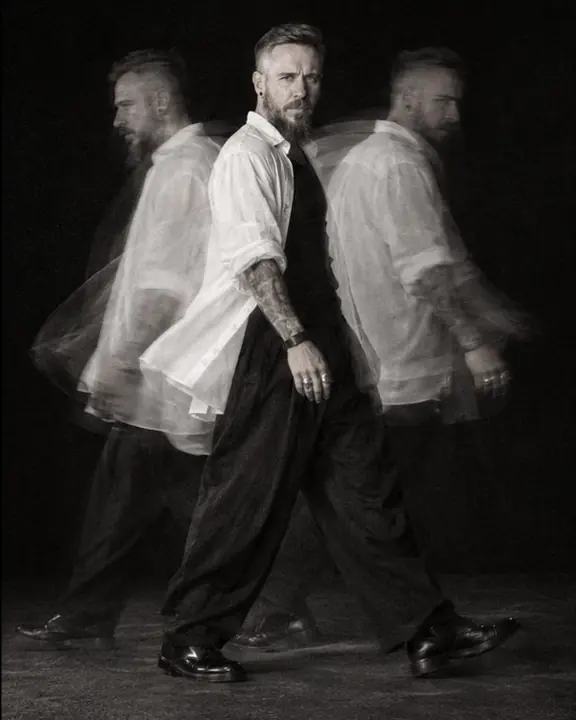 A man walks in a small circle on black, three translucent overlapping phases of his body, one of them solid