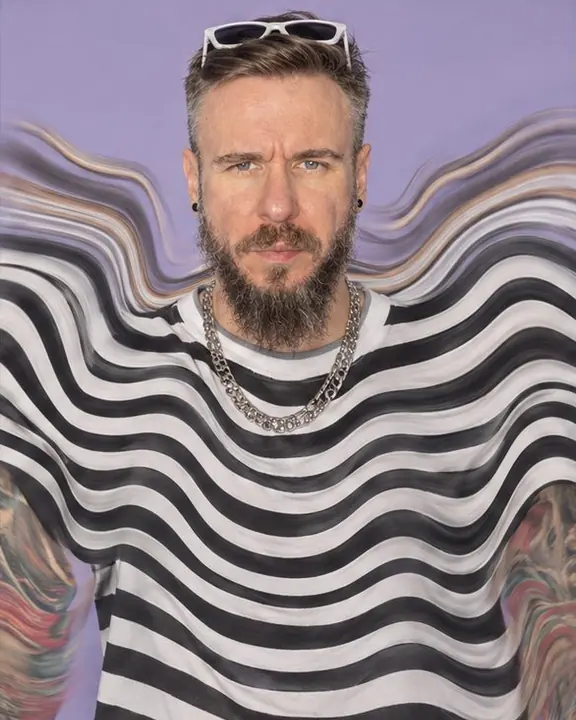 Waist-up of a bearded man in a striped shirt bending into concentric waves around his still face