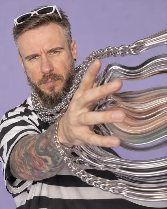 Silver chains and a hand stretched into liquid silver ribbons against a flat pale lilac background