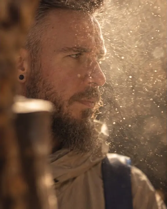 Close-up of a bearded man's eyes with glowing dust particles floating in the sunbeam in front of them