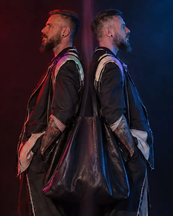 Two red and blue versions of a man standing back to back, an oversized black leather tote between them