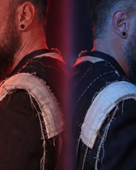 Detail of an exposed shoulder pad and suit lining doubled across a prism seam in red and blue light
