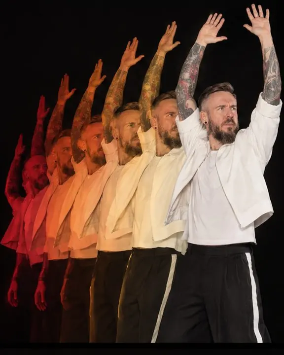 Waist-up of a man sweeping his arms from low to high in seven colored phases fanned out like a deck of cards