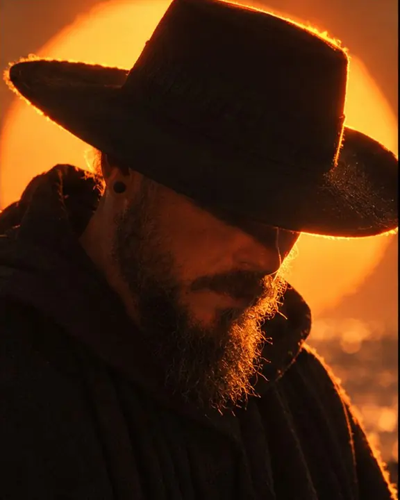 Detail of a wide hat brim edge glowing against the setting sun, warm haze shimmering around it