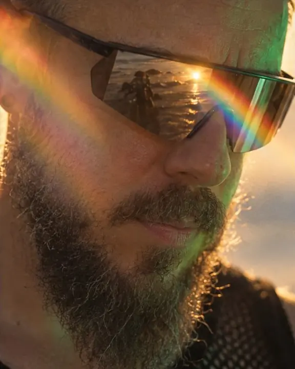 Close-up of wraparound shield sunglasses on a bearded man catching a rainbow spectrum from a prism