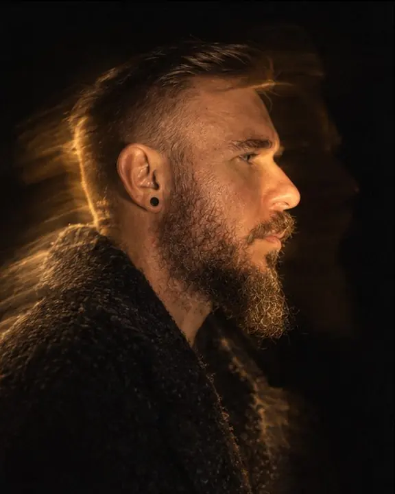Profile of a bearded man painted with light along its edge, a faint ghost of a second profile beside it